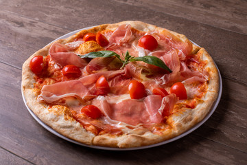 close up of fresh baked ham, cheese and tomato cherry pizza