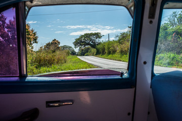 Empty road seen from a backseat of an old car