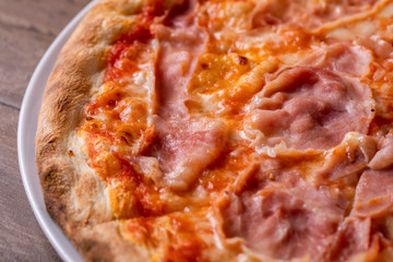 details of pizza with mozzarella and ham on a wooden background