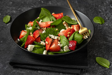 Close up of refreshing spring salad with strawberries, spinach, feta and nuts