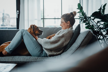 Woman cuddles, plays with her dog at home because of the corona virus pandemic covid-19