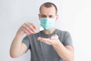 coronavirus protection, hand hygiene and disinfection concept - man in mask using sanitizer gel