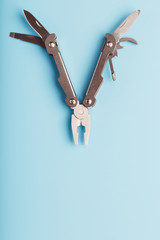 The multitool multi-function tool hovers on a blue background. The concept of an expanded multi-tool with free space.