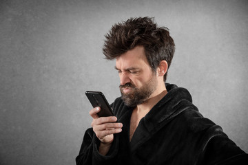 Man in bathrobe with funny hair and mobile phone isolated background