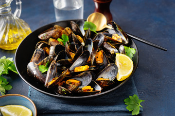 Close up of a plate with freshly coocked mussels on dining table - obrazy, fototapety, plakaty