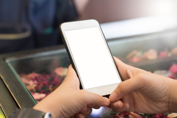 Mockup image of a man's hand holding white mobile phone with blank black desktop screen on thigh in cafe