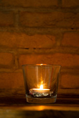 candle lit inside a glass with pine cone