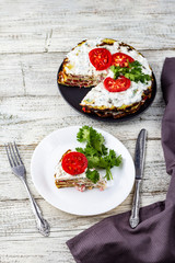Zucchini cake with tomatoes and fresh parsley on white wooden background.