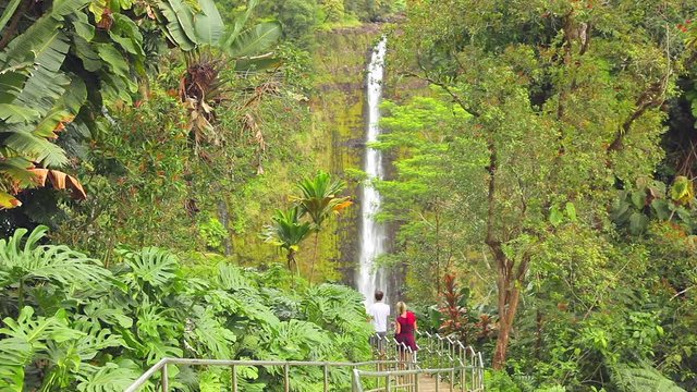 Two people enjoying a walk over a bridge and down to Akaka Falls in a tropical park just north of Hilo on the island of Hawaii