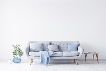 Bright room interior mockup for grey and light blue couch, beside wooden coffee table with books on it. Blue glass vase with green plant on the other side. White bright wall. Empty space concept. 