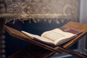 Quran islamic holy book on dark background with with blurred traditional carpet for reading in...