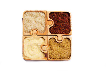 Corn grits, bulgur, quinoa and rice in a wooden puzzle form on a white background. Isolated object