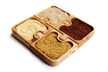 Corn grits, bulgur, quinoa and rice in a wooden puzzle form on a white background. Isolated object
