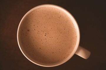 Cup of hot tasty coffee with cream on wooden table closeup. Top view. Good morning. Breakfast time.