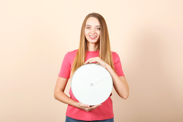 Girl holds a mechanical clock on a colored background