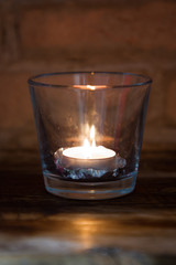 candle lit inside a glass with pine cone