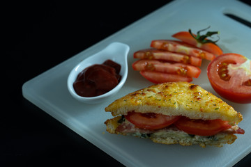 Baked croque monsieur spinach and ham sandwich with tomato sauce, isolated black background.