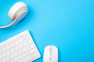 Modern devices for your leisure at home. Work from home. White keyboard, mouse and headphones on blue background, top view.