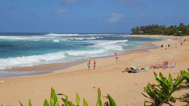 People running in the sand and enjoying Sunset Beach on the island of Oahu in Hawaii.