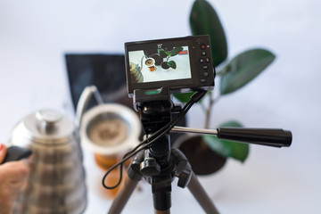Recording video on the camera on tripod of coffee preparation process on white background.