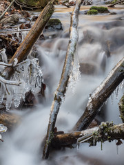 Langzeitbelichtung eines kleinen  vereisten Gebirgsbachs in der winterlichen Landschaft.