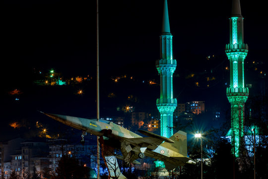 night photo of jet fighter jet and mosque behind it