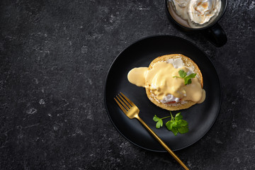Top view of a poached egg in a black plate and black background