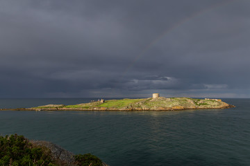 Blick vom Dillon’s Park auf die kleine unbewohnte Insel Dalkey Island mit Kirchenruine, Martello-Turm und einem Regenbogen an der Ostküste Irlands