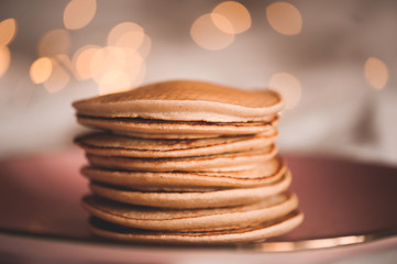 Tasty pancakes in stack on plate over glowing lights closeup. Good morning. Breakfast time.