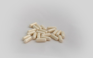 Bunch of pills on white background. Selective focus. Light yellow capsules are scattered over a white background. Virus cure.