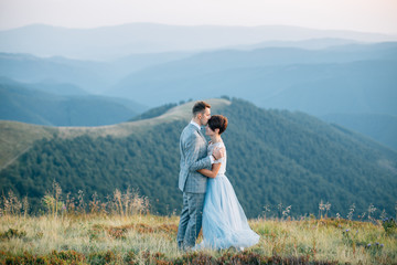 Wedding couple kissing in mountains at sunset