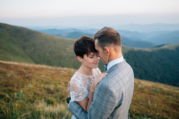 Beautiful european couple embracing in mountains. Outdoor wedding.