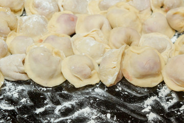 Dumplings, cooked at home, lie on a plate, sprinkled with flour.