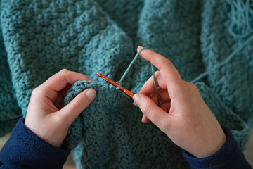 Woman's hands crochet background.  Looking down on Woman's hands  Crocheting blue yarn
