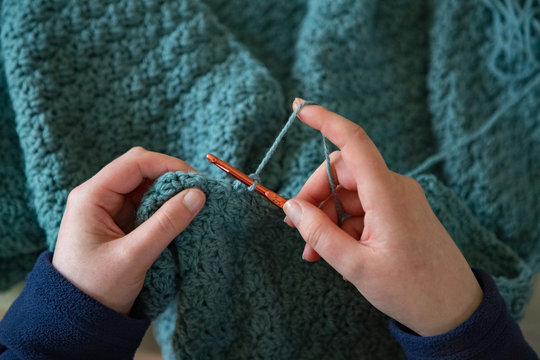 Woman's hands crochet background.  Looking down on Woman's hands  Crocheting blue yarn