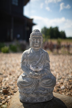 Large grey Buddha statue on the street.