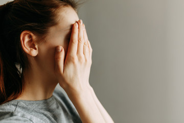 Stop domestic violence against women. The girl covers her face with her hands and cries.