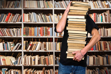 A young man holds a stack of books