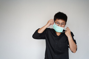 The man doing wearing face hygienic mask for prevention global covid-19 virus pandemic. The corona-virus from wuhan is dangerous. Use his hands pull mask into face.
