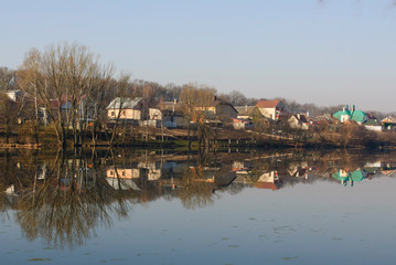 Obraz premium Spring morning on the lake, reflection of houses in the water, silence and calm of dawn