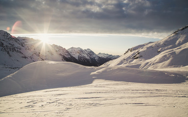 The sun rises among the snowy Alpine peaks.
