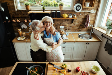 Embraced mature couple having fun while preparing food in the kitchen.