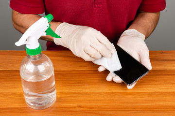 Cleaning with cell phone gloves on wooden table.