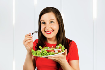 Portrait of a cheerful athletic woman eating healthy salad. Concept of losing weight, sports and healthy eating