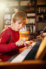 Young boy playing the piano in a sunny living room