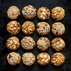 Oat cookies sprinkled with various seeds and nuts on a black background, top view