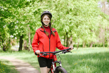 girl on a bike walk in a green park summer day dressed in a bicycle uniform