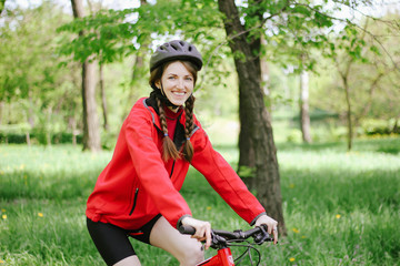 girl on a bike walk in a green park summer day dressed in a bicycle uniform