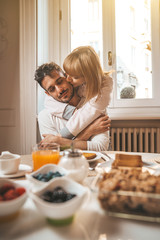 Couple in love eating breakfast early in the morning in the kitchen at home and having a good time.