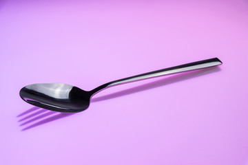 Löffel wirft Schatten einer Gabel auf einen rosafarbenen Hintergrund